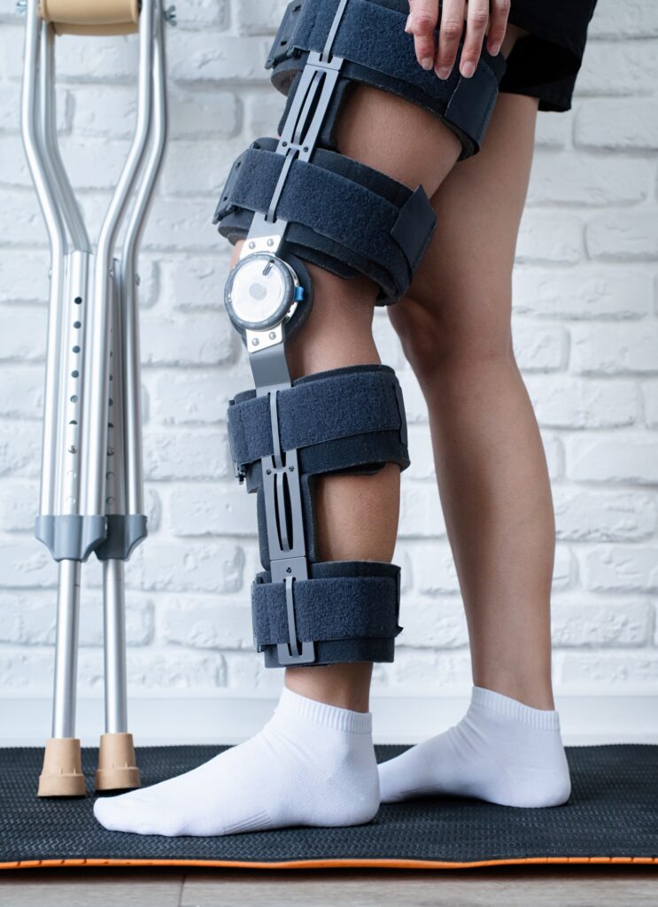 Female wearing knee orthosis or knee support brace after surgery on leg