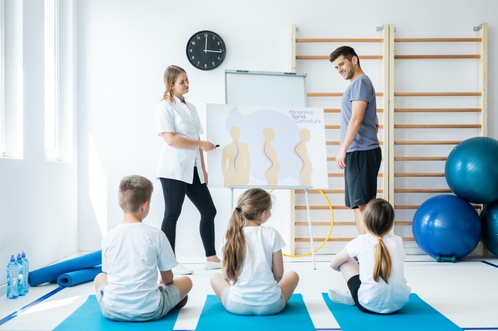 Trainer and nurse explaining to small children types of spine problems